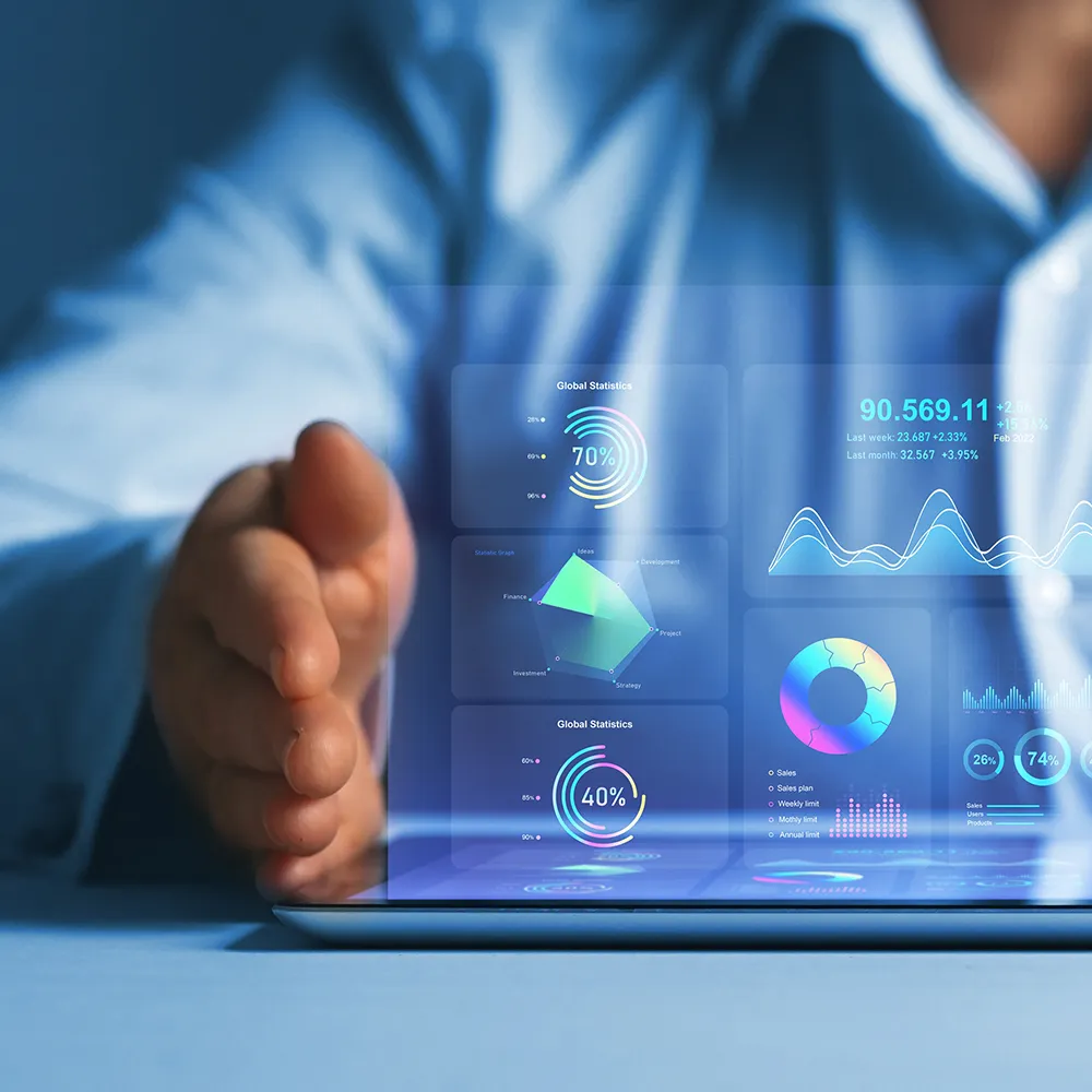 Business professional reviewing futuristic digital dashboards projected above a tablet, showing charts, graphs, and data visualisations in vibrant colours.